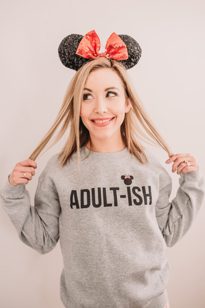 Brianna K wearing adultish disney sweatshirt with tips on what to wear to disney for a family outfit ideas coordinating disney clothing wardrobe