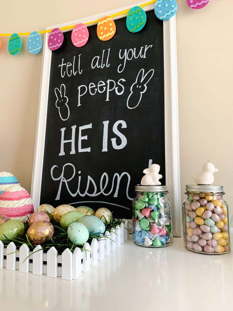 Brianna K bitsofbri easter chalkboard sign that says tell all your peeps he is risen Easter egg banner Easter egg decor easter candy jars that are DIY from the dollar tree with spring colored Hershey kisses and Cadbury eggs with a duck and bunny hot glued on. top