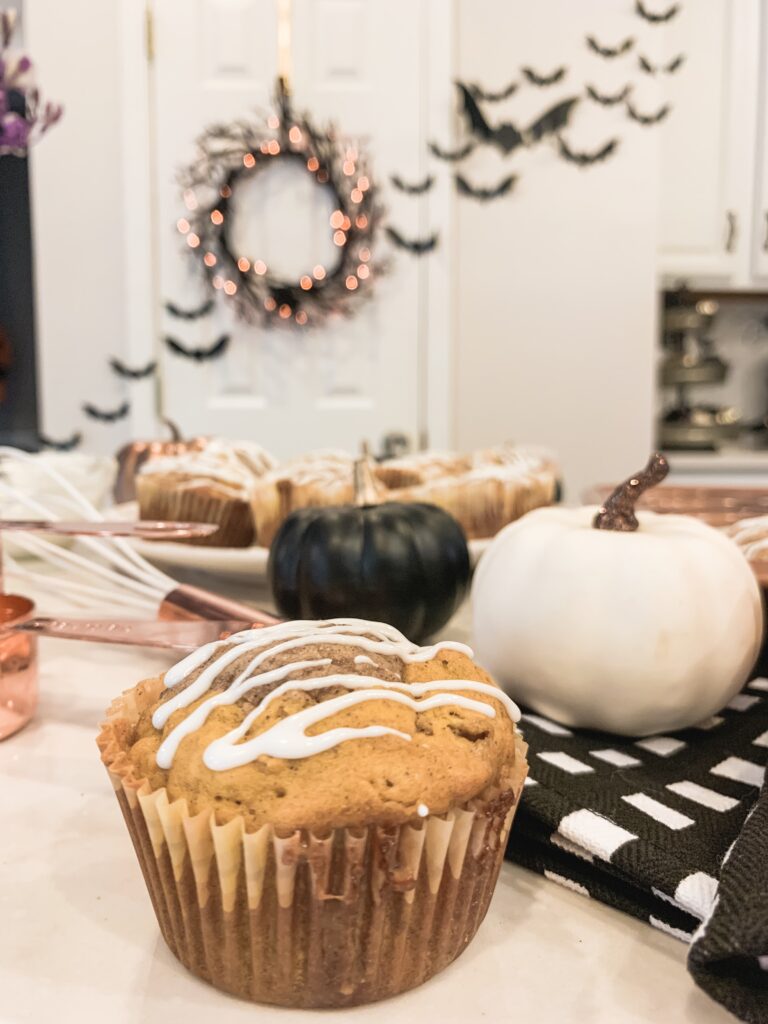 pumpkin muffin with white drizzle icing with rose gold utensils and pumpkins 