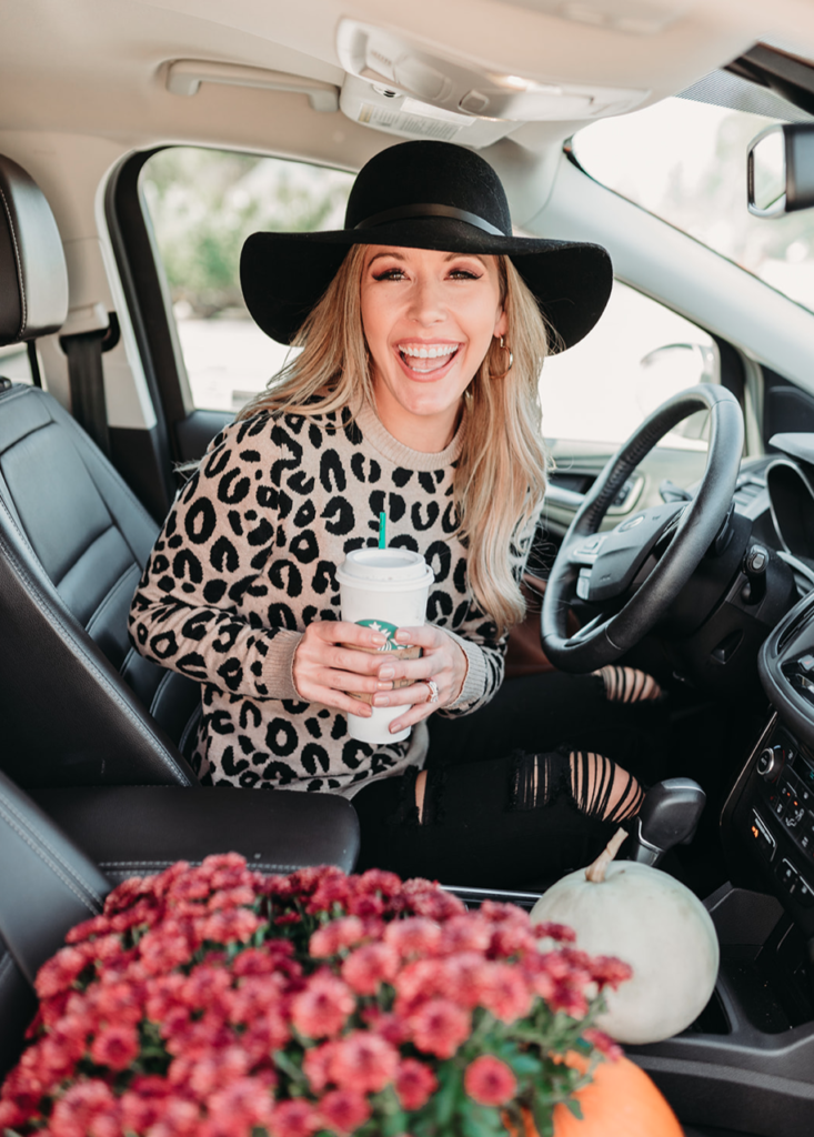 Brianna K bitsofbri in her car with black floppy hat leopard sweater and Starbucks productive routine and daily schedule of a stay at home mom blog post and day in the life youtube video 