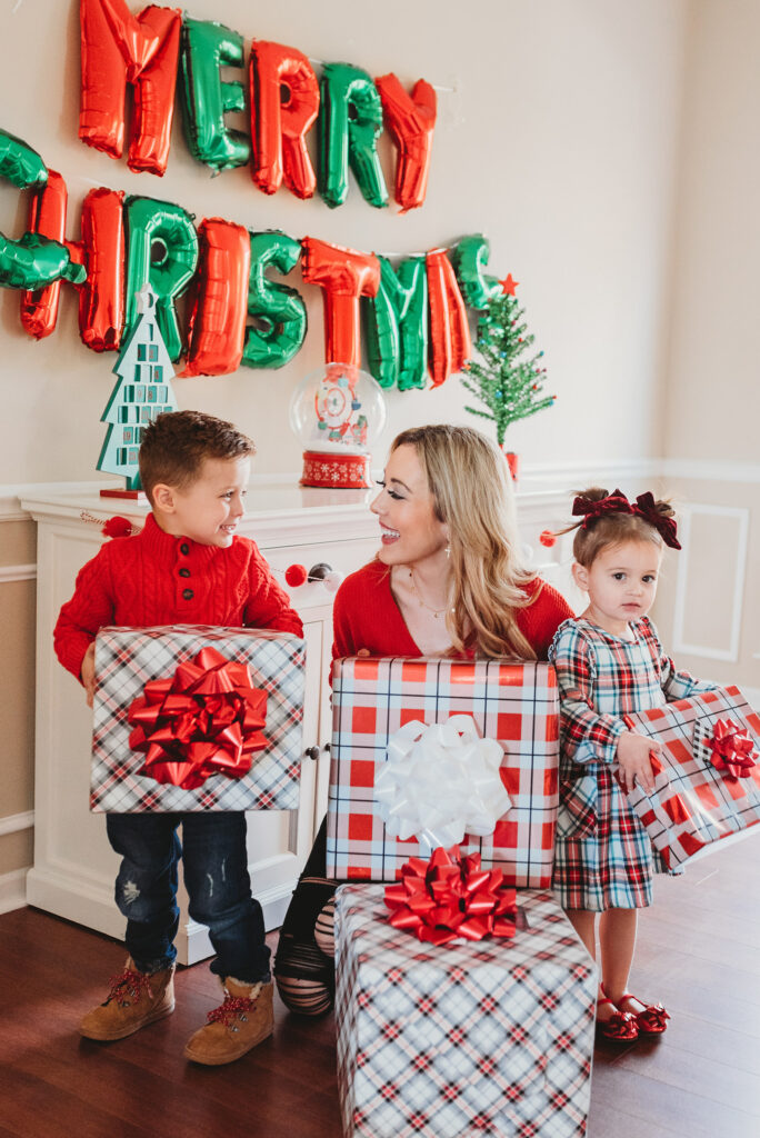 mom and two kids holding a pile of christmas presents with merry christmas balloons Brianna K Landon and Presley holiday gift guide christmas 2019 blog post 