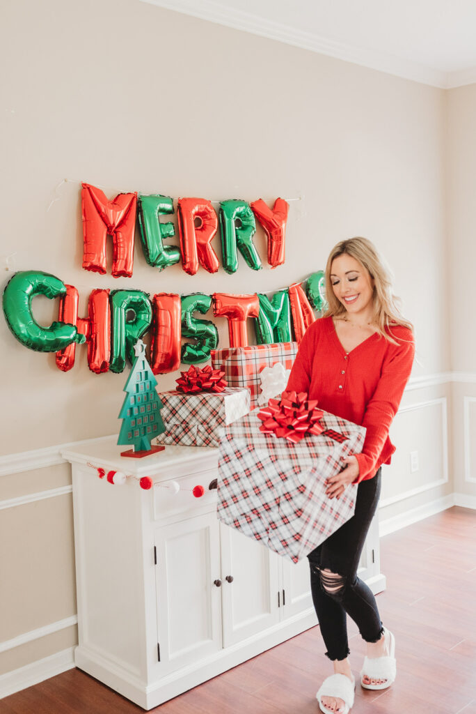 mom holding present in front of Merry Christmas balloons Brianna K Landon and Presley holiday gift guide christmas 2019 blog post 
